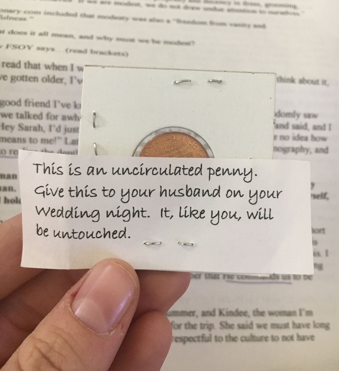 Photo of new penny in case with a slip of paper stapled to it. The slip of paper reads, "This is an uncirculated penny. Give this to your husband on your wedding night. It, like you, will be untouched."