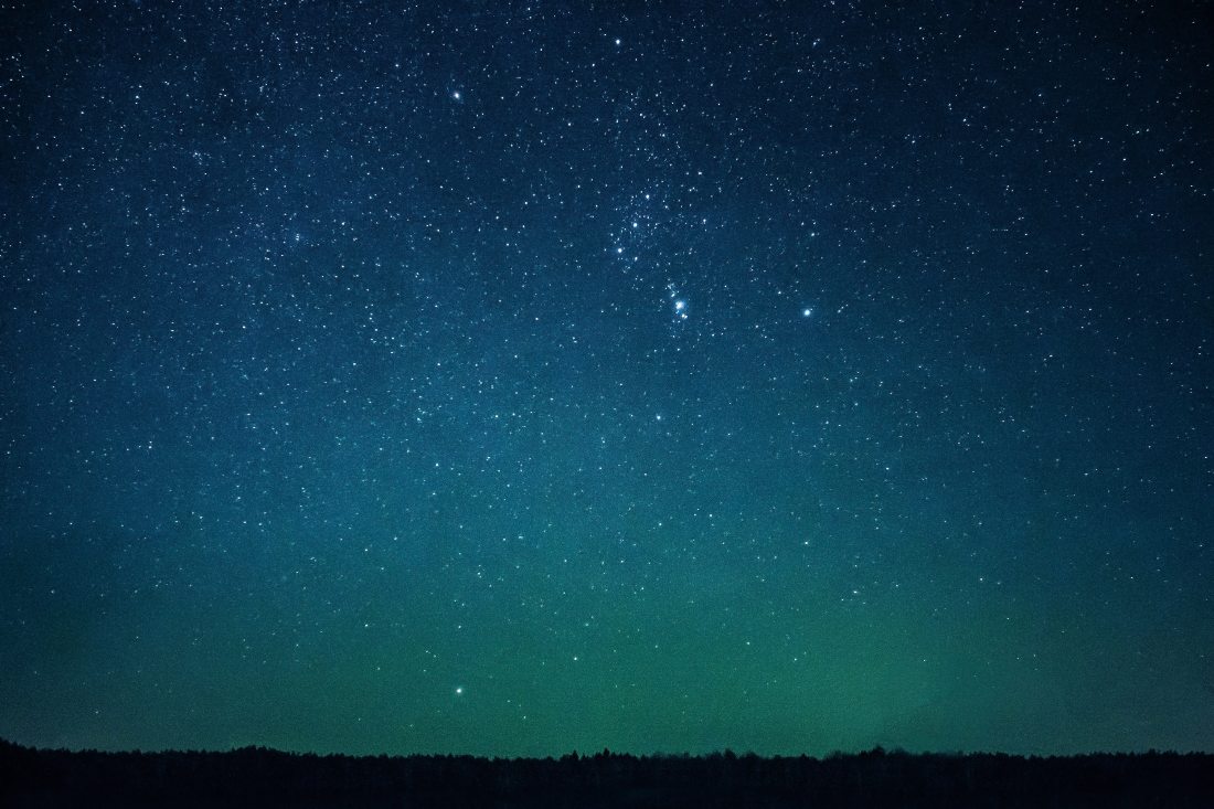 A starry sky just after dusk, with a greenish tint to the horizon and a darkening blue as you go up.